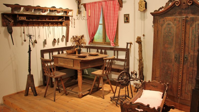 Belvedereschlössl/District Museum Stockerau, © Stadtgemeinde Stockerau Historic farmhouse parlor with wooden furniture, spinning wheel and cradle.