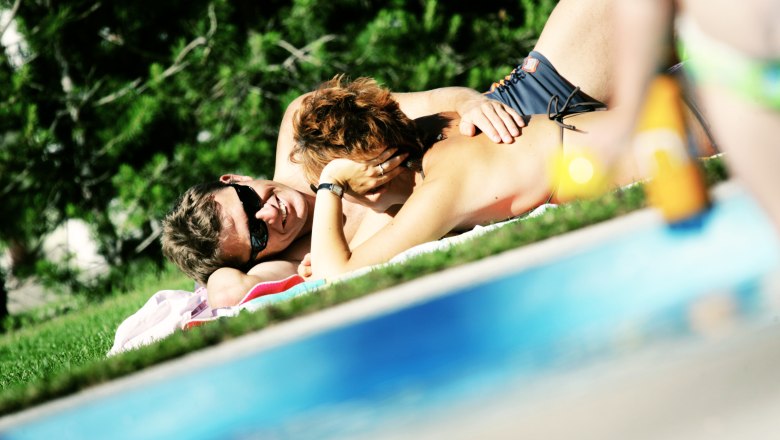 Mitterbach outdoor pool, © weinfranz.at A couple relaxes on a lawn by the pool at the Mitterbach outdoor pool.