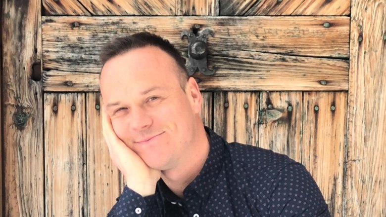 Herwald Hauleitner, © Hauleitner Person leans against an old wooden door with a smile.