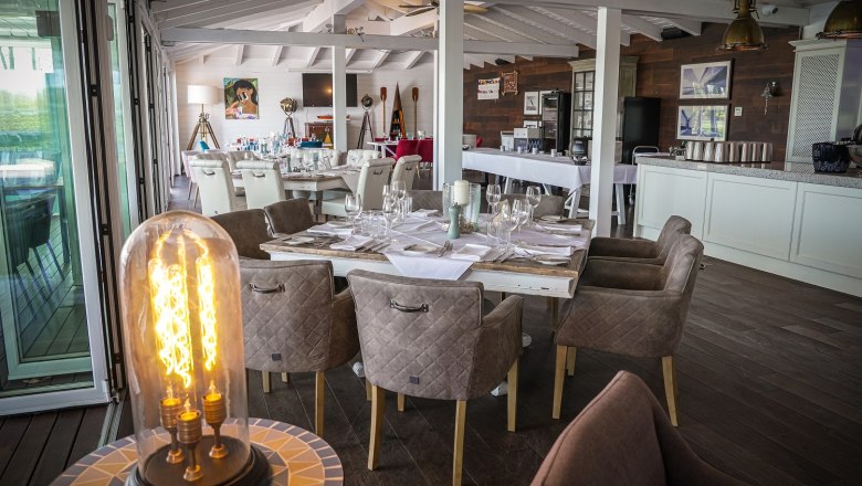 Hotel DCC, © Diamond Country Club Set table in the dining room. A lamp in the foreground. The room is decorated in white and brown.