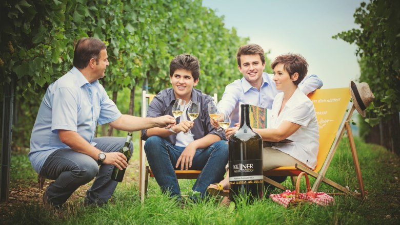 Pension Rudi, © Pension Rudi Four people sit in a vineyard and toast with wine glasses.