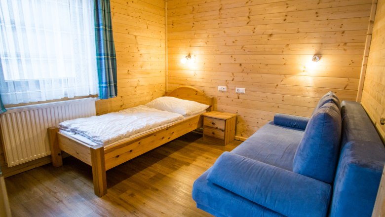 Vacation home "Romantic" children's room, © Familie Morgenbesser Children's room with wooden walls, single bed, blue sofa and bedside table.
