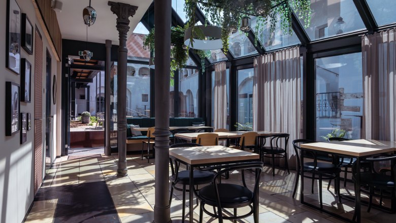 forty yard, © Niederösterreich Werbung / Maximilian Pawlikowsky Interior view of a modern café with glass roof and plants.