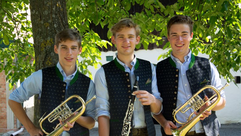 Honsig Buam, © Thomas Honsig Three young men in traditional dress with wind instruments in front of a tree.
