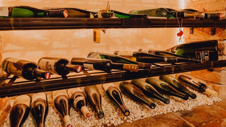 Wide range of wines, © Niederösterreich Werbung/Klaus Engelmayer Wine bottles on a shelf on white stones.