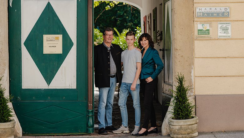 Haimer family, © Haimer/Michael Reidinger Three people are standing in an archway in front of a building labeled 'Harald Haimer'.
