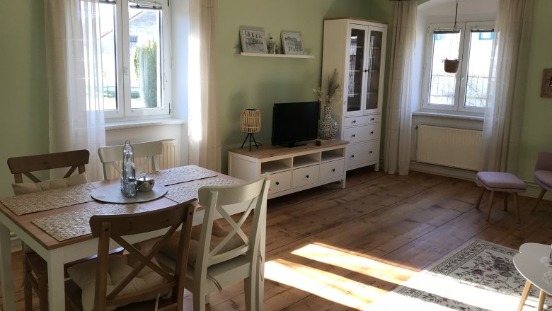 Lounge with dining area, © Martina Braun Bright room with dining table, chairs, TV cabinet and large windows.