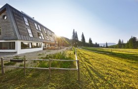 Knofeleben Naturefriends House on the Gahns, © Wiener Alpen / Bene Croy Naturfreundehaus Knofeleben in a sunny mountain landscape with solar panels on the roof.