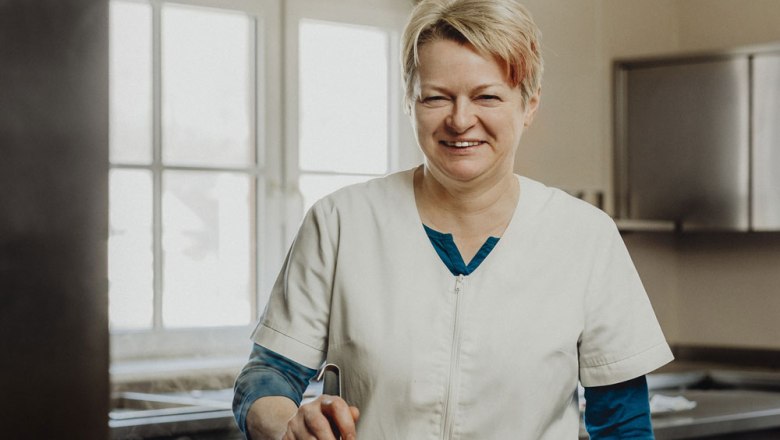 Cook Anni Pichler, © Niederösterreich Werbung/Sophie Menegaldo A smiling woman in a white chef's jacket stands in a kitchen.