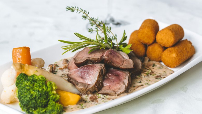 Venison leg with croquettes, © Niederösterreich Werbung/David Schreiber Gourmet dish with meat, vegetables and croquettes on a white plate.