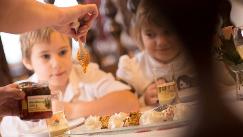 Alpenhotel Ensmann, © dphoto.at Two children watch as honey is drizzled on a dessert.