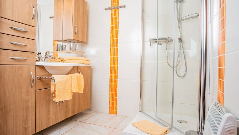 Bathroom, © Georg Pomassl Modern bathroom with wooden furniture, shower and orange accents.