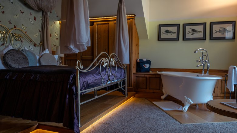 Hotel ResidenzWachau, © Niederösterreich Werbung / Maximilian Pawlikowsky Luxurious hotel room with four-poster bed and free-standing bathtub.