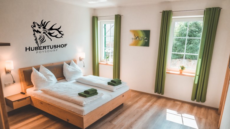 Guest room, © Matthias Auer Modern guest room with double bed, green curtains and wall decoration at Hubertushof Poysdorf.