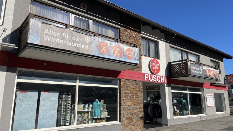 Sport-Puschi-Sportshop (c)Sport Puschi, © Sport Puschi Exterior view of a sports store called Puschi with large windows and advertising banners for winter equipment.
