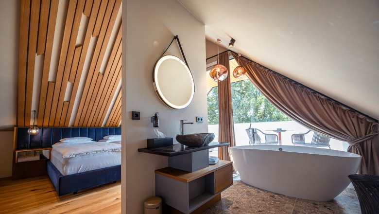 Wine domicile Hagn, © Niederösterreich Werbung / Maximilian Pawlikowsky Modern hotel room with wooden ceiling, free-standing bathtub and balcony.