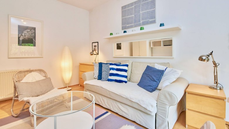 Top 2 - Living room, © VP FeWo OG Cozy living room with sofa, cushions, armchair, floor lamp and coffee table.