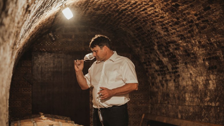 Winemaker Martin Hirtl, © Michael Reidinger Man in a wine cellar smelling a wine glass.