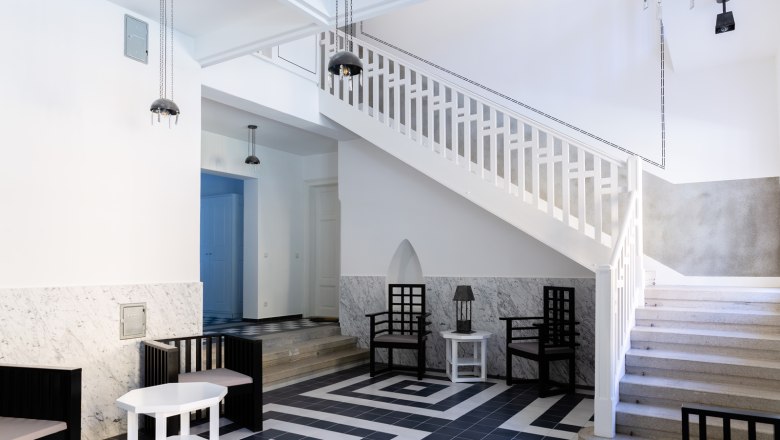 Entrance area, © Thalhof, Katrin Nusterer Modern entrance area with staircase, black and white tiles and minimalist furniture.