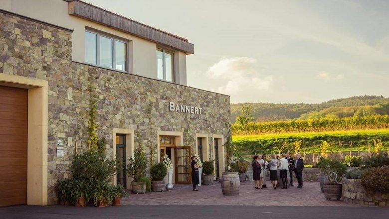 Bannert Winery, © Weingut Bannert Bannert winery with people in front of the building and vineyards in the background.
