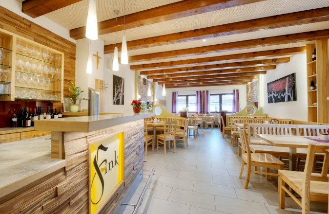 Wine tavern Weinhof Fink, © Philipp Monihart Interior view of a cozy dining room with wooden furniture and a bar in Heurigen style.