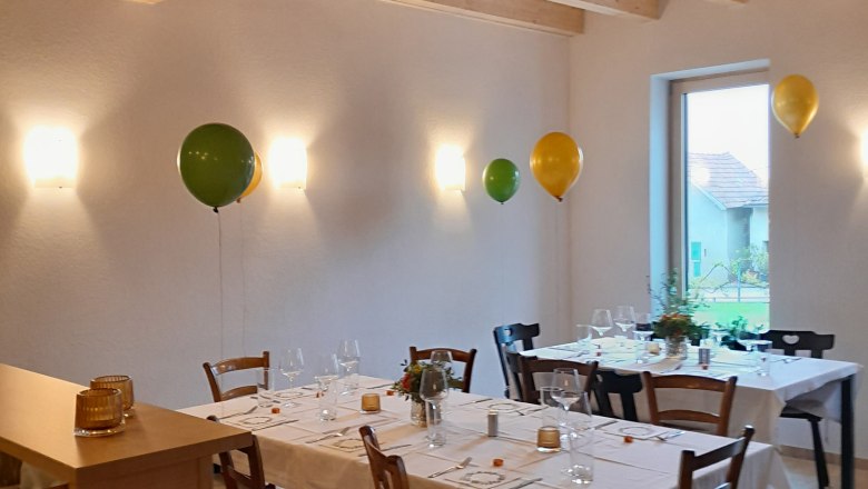 Distillery - Kollmann, Destithek, © Brennerei - Kollmann A festively laid table in a room with a wooden beamed ceiling and balloons on the wall.