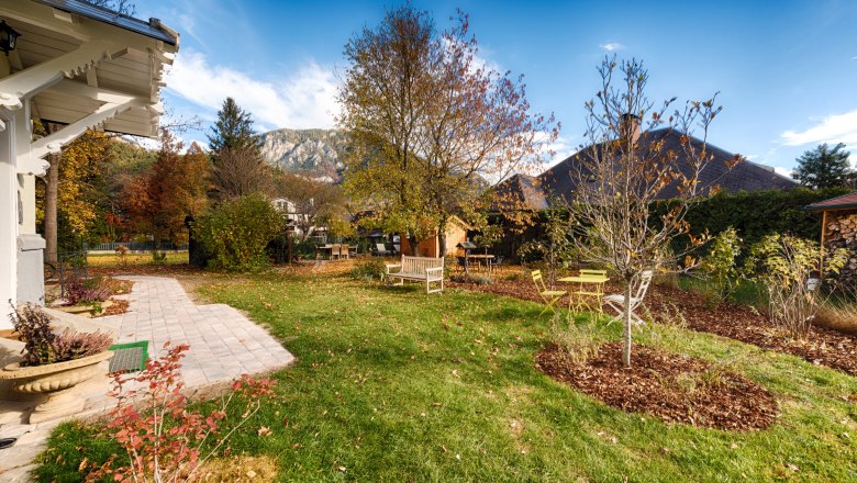 Autumn garden, © VP FeWo OG An autumnal garden with trees, benches and a paved path. Mountains and a blue sky can be seen in the background.