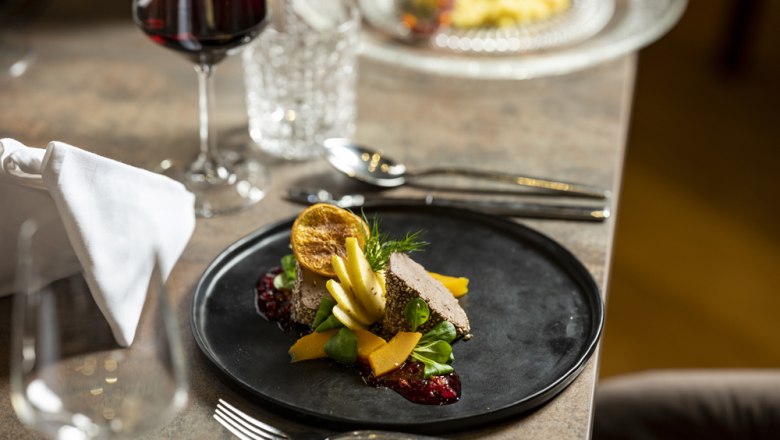 Poultry liver pâté, © Niederösterreich Werbung/Michael Reidinger Gourmet dish on a black plate with red wine in the background.