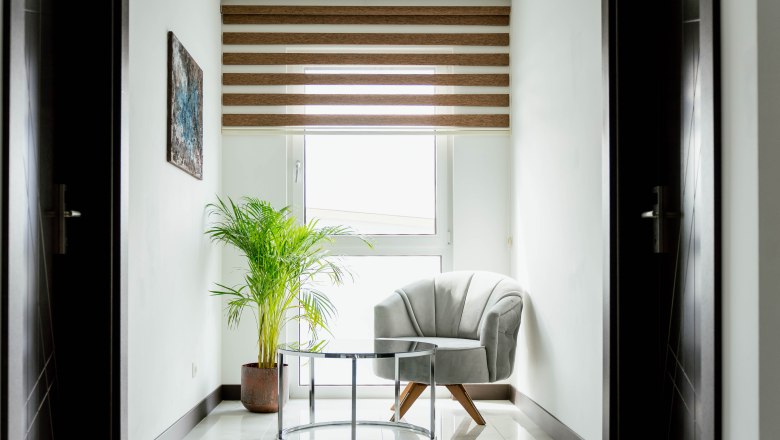 Hotel Lamede, © Hotel Lamede Bright corner with armchair, glass table and plant in front of a window with blinds.