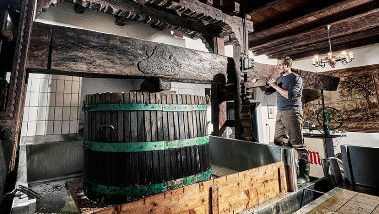 Roland Minkowitsch Winery, © Herbert Lehmann A man works at a traditional wine press in a winery.