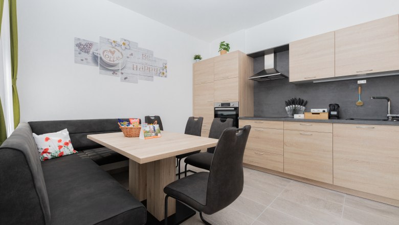 Communal kitchen, © Schönfelderhof Modern kitchen with wooden furniture, dining table, corner bench and chairs.