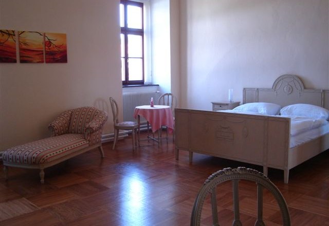 Jakob-Kern Guest House, © Jakob-Kern Gästehaus Bright guest room with antique bed, chaise longue and small table.