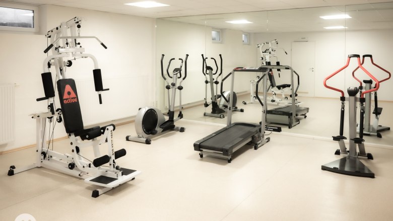 Fitness room in the wellness world, © TheVerve-Agentur (theverve.at) A fitness room with various training equipment such as a treadmill, exercise bike and weight station in front of a large mirror.