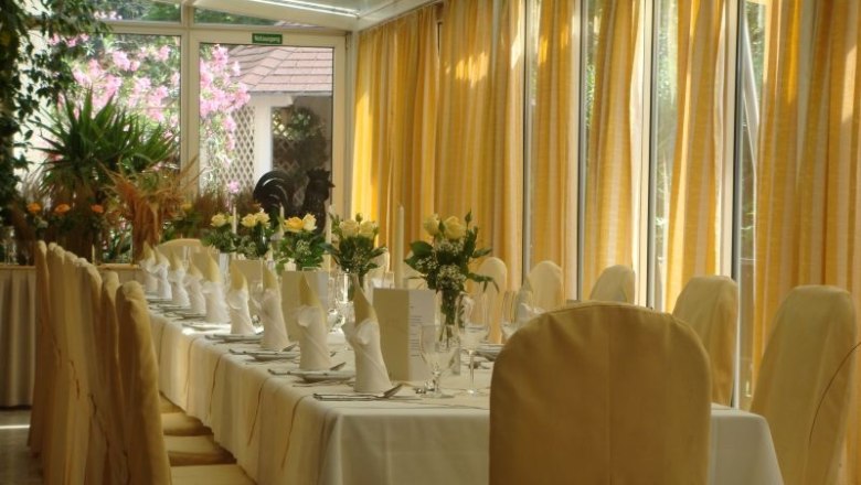 Conservatory, © Landgasthaus Hotel Muhr Elegant conservatory with table setting and yellow curtains.