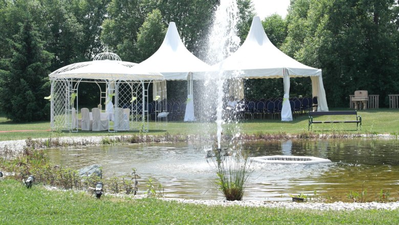 Wedding pavilion, © Besta Betriebs GmbH A wedding pavilion and tents next to a pond with a fountain in a garden.