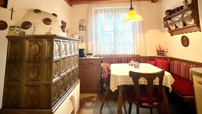 Kitchen_HeidisPlace, © Wiener Alpen Cozy kitchen with tiled stove, wooden table and corner bench.