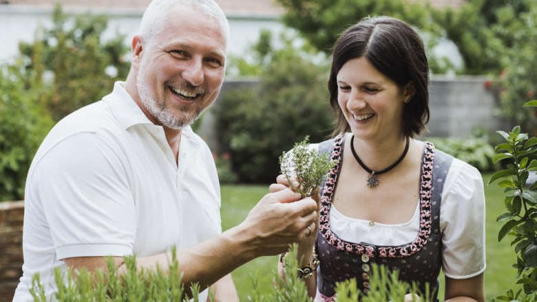 Carina and Hannes Windhör, © Niederösterreich Werbung/David Schreiber A man and a woman stand smiling in a garden looking at herbs.