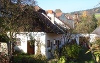 Kranzer horse farm, © Kranzer A rural building with white walls and red tiled roofs, surrounded by trees and bushes.