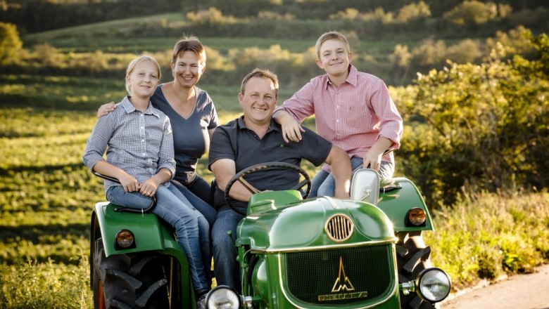 Sunday outing, © Astrid Bartl Family on a green tractor in a rural setting.