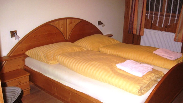 Room, © Gruber Johann Wooden bed with yellow bed linen in one room.