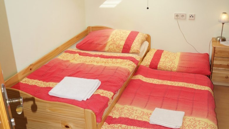 Single room with extra bed for children, © Reep A single room with a bed and an extra bed under a skylight. The beds are covered with red and yellow blankets.