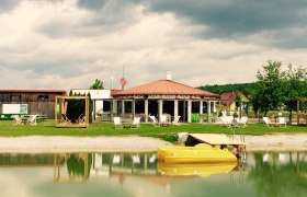 Jaidhof recreational pond, © Gemeinde Jaidhof A recreational pond with a yellow pedal boat, deckchairs and a pavilion in the background.