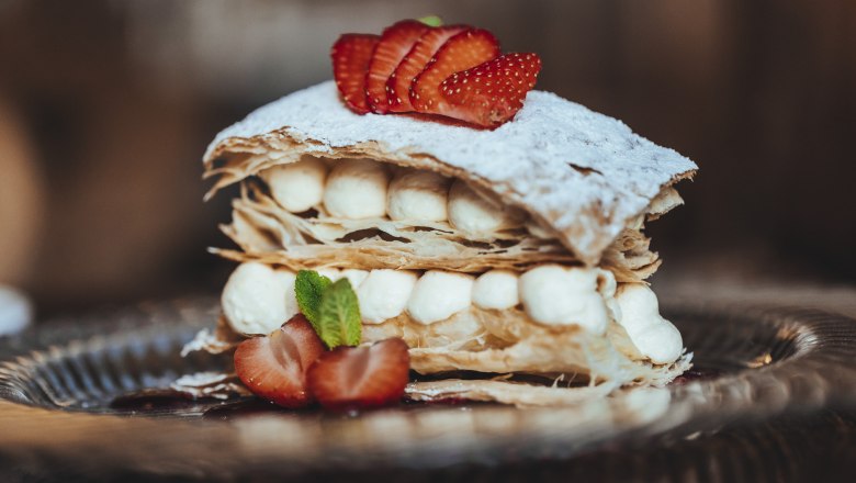 Cream slice, © Niederösterreich Werbung/David Schreiber A cream slice with puff pastry, cream and strawberries on a plate.