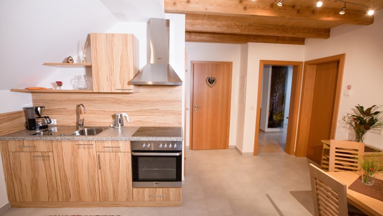 Vacation apartment Muck, © schwarz-könig.at Modern kitchen with wooden decor, dining table and flowers.