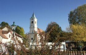 Parish church Walpersbach, © Roffeis Heinz Walpersbach parish church with tower and surrounding buildings, surrounded by trees and bushes under a blue sky.