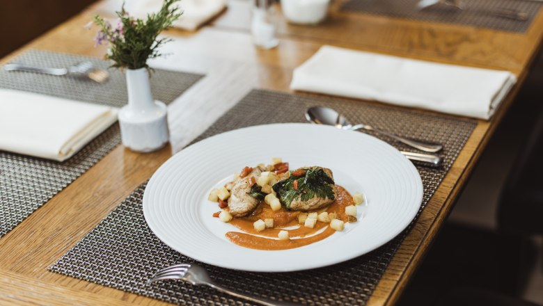 Waller Szeged cabbage meat, © Niederösterreich Werbung/David Schreiber Elegant dish on a white plate, decoratively arranged on a wooden table.