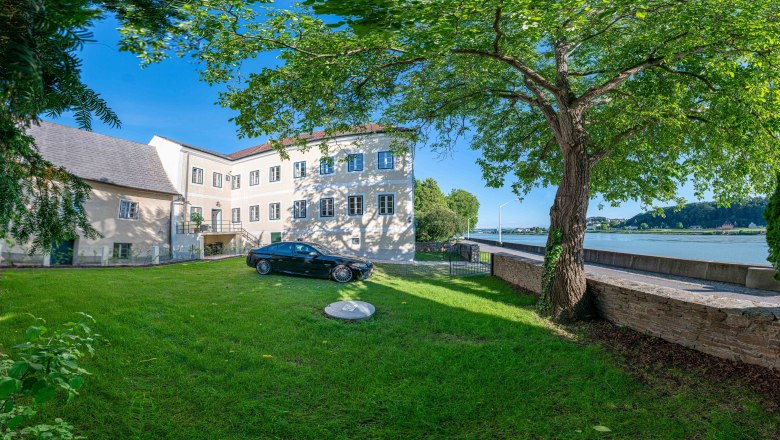 Old post office exterior view with Danube, © Aumüller Caroline Exterior view of an old post office with tree and car in the foreground, Danube in the background.