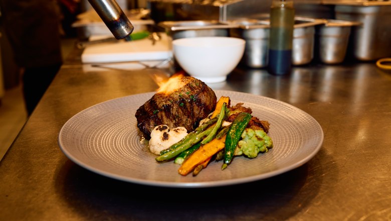 Wolfgang Puck Kitchen + Bar, © Flughafen Wien Wolfgang Puck Kitchen + Bar, meat is flambéed on the plate