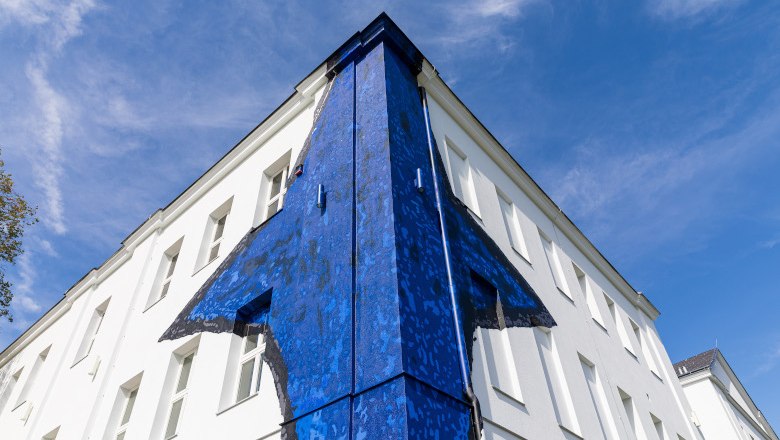 Museum Gugging, © NÖ Museum Betriebs GmbH/Ludwig Schedl Building with blue wall art on the corner, against a blue sky.