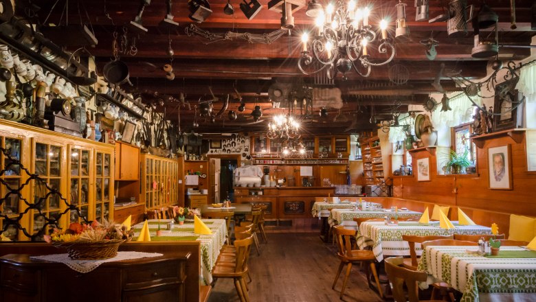 Gasthof Scherrerwirt, © Gasthof Scherrerwirt, Foto: David Rath Interior view of a traditional inn with wooden furniture and decorative objects on the ceiling.